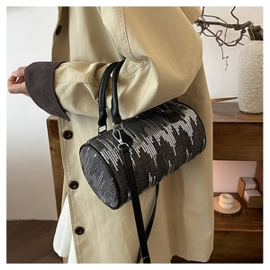 Detail of vintage denim cylinder bag with white sequins worn with a beige trench coat