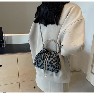 Detail of leopard print bucket bag with silver chain strap and pearl drawstring accents