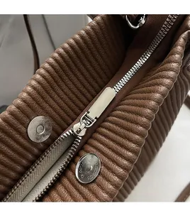 Detail of brown quilted leather tote bag featuring a silver zipper and magnetic buckle