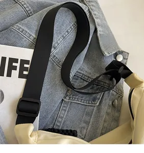 Dettaglio della tracolla regolabile nera su una borsa tote grande bianco crema