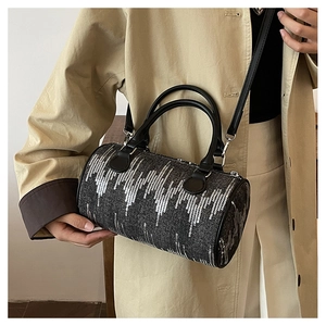 Detail of gray tweed barrel bag featuring shimmering silver sequins and black leather strap