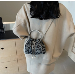 Detail of leopard print bucket bag featuring metallic ring handle and pearl drawstring charms