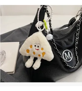 Detail of creative cheese plush charm with cute facial features on a black quilted chain bag