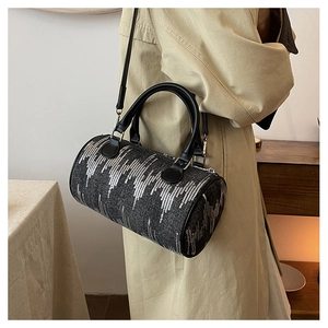 Detail of vintage denim cylinder bag with silver sequins and black leather straps