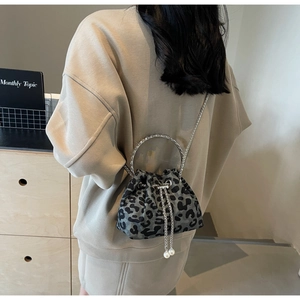 Detail of mini bucket bag with cow pattern, metal handle and tassel with pearl charms