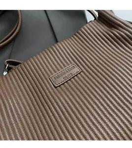 Close-up of pleated texture on a large coffee brown tote bag with leather logo patch