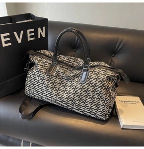 Close-up of jacquard travel bag with geometric patterns and leather handles on black sofa