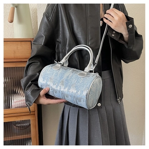 Detailed close-up of light blue denim Boston bag featuring vertical silver sequins and strap