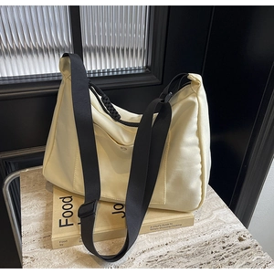 Dettaglio della borsa tote in nylon crema con tracolla nera e tasca con bottone a pressione