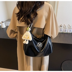 Detail of black pleated leather shoulder bag with silver M logo and plush smiley charm