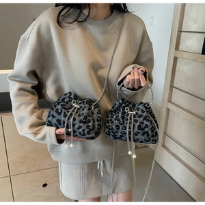 Detail of leopard print bucket bags with metal ring handles and pearl drawstring accents