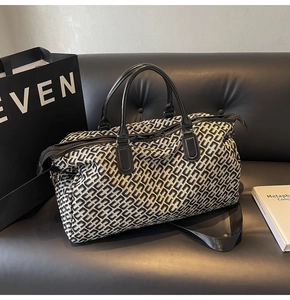Detail of black and white geometric jacquard canvas bag with leather handles on sofa