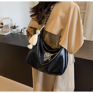 Detail of black crinkle leather shoulder bag featuring silver M logo and plush charm