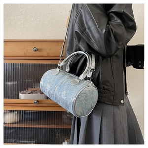 Detail view of light blue denim Boston bag with shiny silver sequins and metallic handles