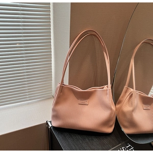 Detail of pleated shoulder bag in peach pink with fashion label and mirror reflection