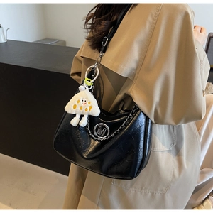 Detail of black glossy crescent hobo bag with silver M logo and plush charm