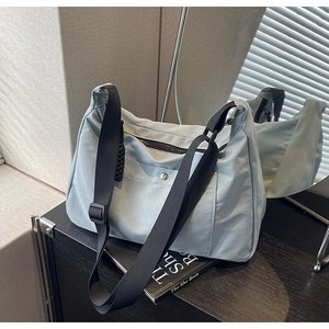 Dettaglio borsa tote in nylon azzurro con tracolla nera e nodo decorativo laterale