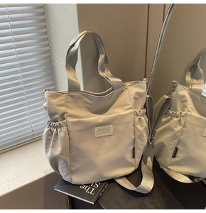 Light gray waterproof nylon tote bag with adjustable shoulder strap and side pockets