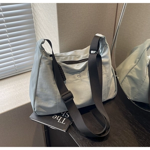 Dettaglio della borsa tote in nylon celeste con tracolla nera e fibbia metallica