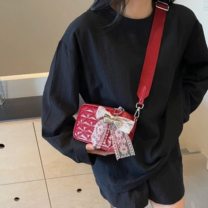 Red quilted leather camera bag for women with lace bow and wide fabric shoulder strap