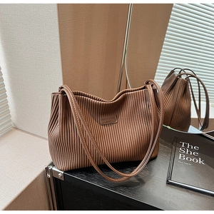 Detail of a brown pleated leather tote bag with FASHION & BAGS logo and slim shoulder straps