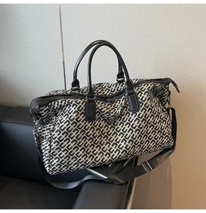 Detail view of large travel duffel bag with black and white geometric pattern on leather sofa
