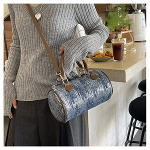 Detail of blue denim pillow bag with silver sequins and brown leather straps in a cafe