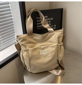 Detail of beige waterproof nylon tote showing front flap pocket and side bottle holders