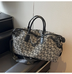 Macro detail of high-capacity travel tote bag with black and white monogram pattern