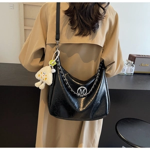 Detail of black wrinkled leather hobo bag with silver M logo and plush charm accessory
