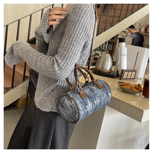 Detail of blue denim jacquard pillow bag with brown leather trim and silver hardware