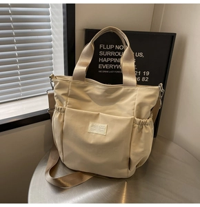 Detail of a beige waterproof nylon tote bag with side pockets and a thick shoulder strap