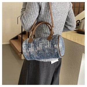 Detail of a denim cylindrical pillow bag with blue sequins and brown leather trim