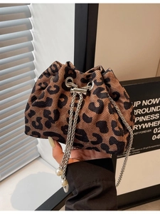 Fashionable cow print bucket bag with metal chain and pearl pendant in a modern style