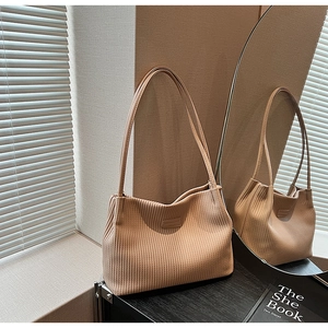 Close-up of khaki tote bag featuring vertical pleated texture and fashion label detail