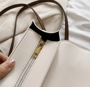 Detail showing smooth gold zipper closure and precise stitching on beige leather bag