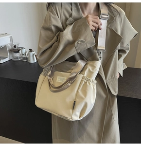 Waterproof cream nylon tote bag with adjustable strap shown in a modern cafe setting