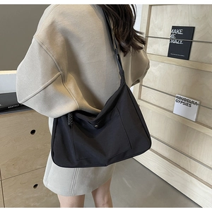 Dettaglio della borsa tote in nylon nero con bottone in metallo e tracolla larga morbida