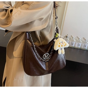 Detail of dark brown wax-leather shoulder bag with silver M logo and plush pendant charm