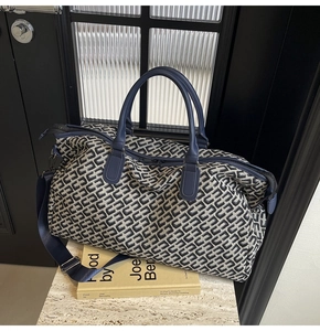 Close-up of blue and white jacquard travel bag with geometric pattern on marble base