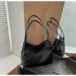 Close-up of black pleated texture tote bag with shoulder straps and logo detail