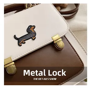 Close-up of dual matte gold hardware buckles on a contrast leather dog embroidery bag
