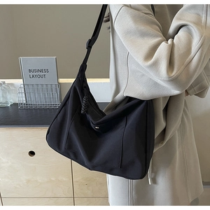 Dettaglio di una borsa a tracolla in nylon nero con tracolla regolabile e tasca frontale