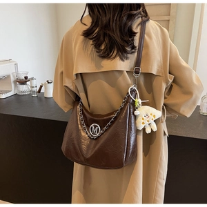 Detailed view of brown cracked leather bag with silver chain and plush star charm