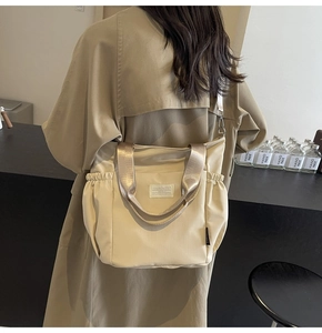 Close-up of beige nylon crossbody bag with side drawstring pocket worn by a model