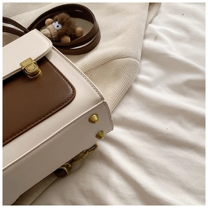 Detail of cream and brown faux leather bag with gold buckle and decorative rivets
