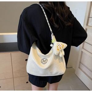 Detail of cream crescent bag with pleated leather, metal M logo, and star plush charm