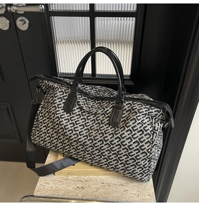Detailed view of duffle bag with black and white jacquard pattern and leather handles
