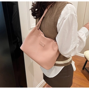 Detail of light pink corduroy tote bag with leather logo tag and shoulder strap