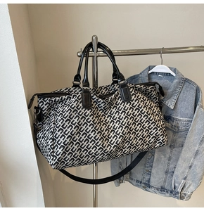 Close-up of geometric jacquard travel bag fabric with black leather handles and shoulder strap